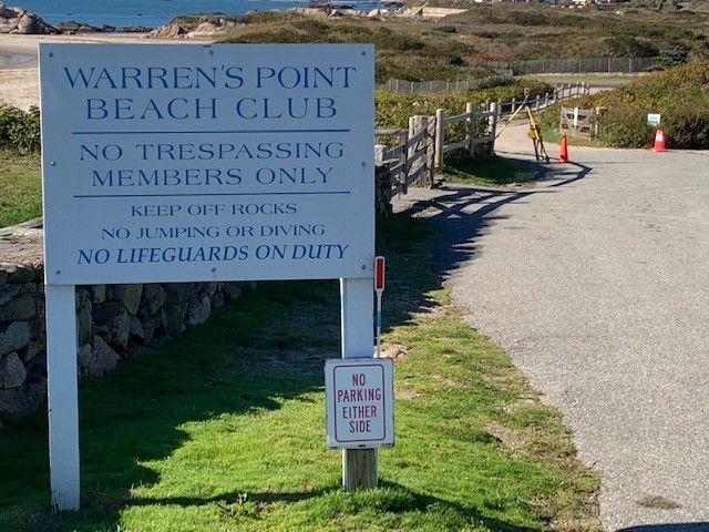 Photo of the Warren's Point Beach Club in Little Compton, Rhode Island. Sign reads: "Warren's Point Beach Club. No trespassing, members only. Keep off rocks. No jumping or diving. No lifeguards on duty." An Able Engineering surveying tripod is seen in the background along the road.